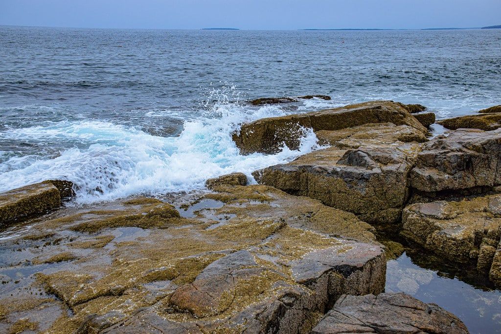 Ozeanwellen brechen sich an der felsigen Granitküste am Schoodic Point im Acadia-Nationalpark.
